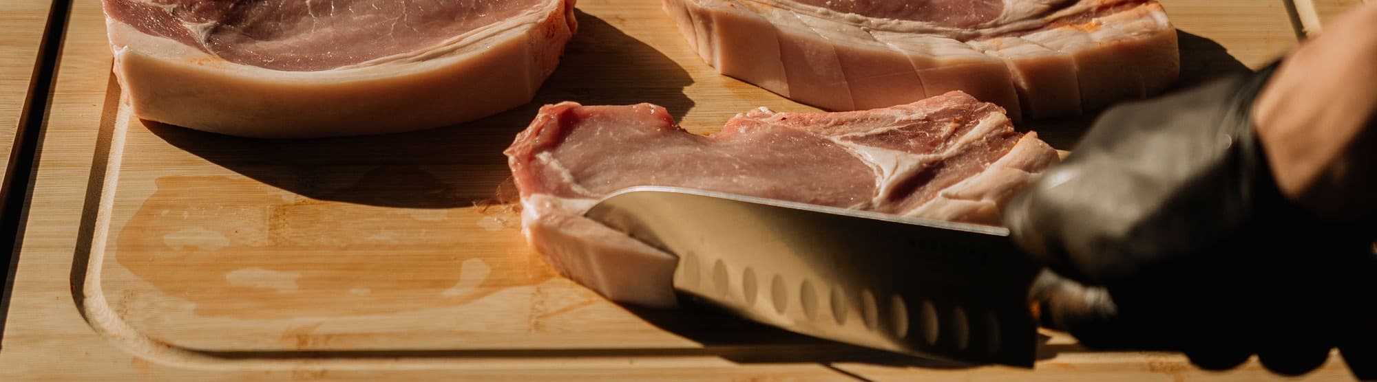 Découpe d'une côte de porc épaisse sur planche en bois